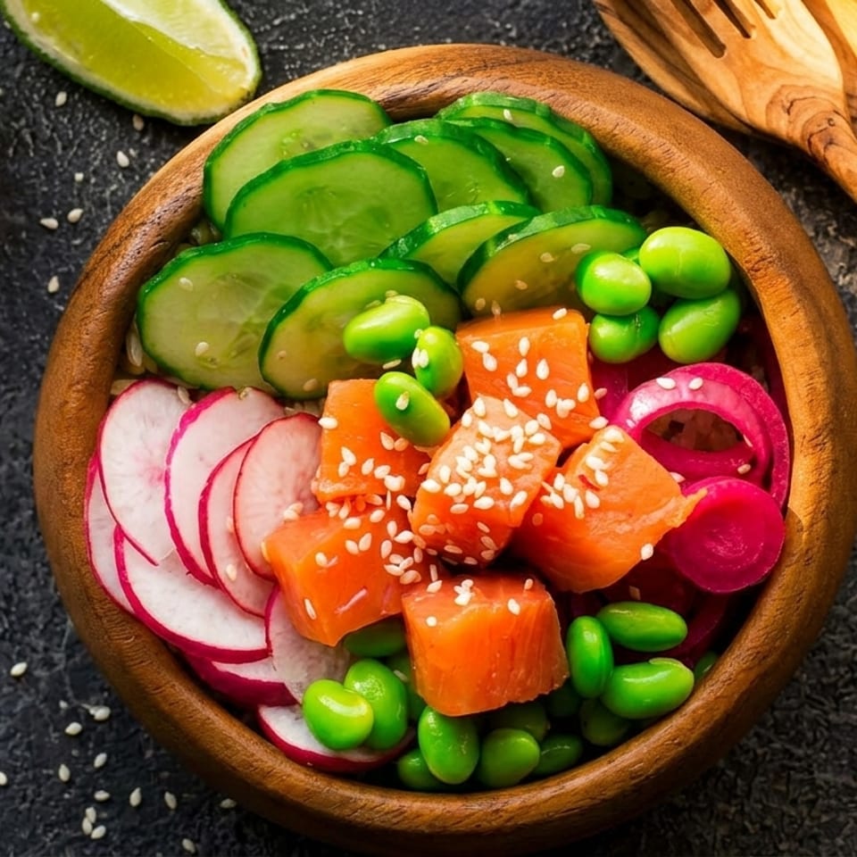 Colorful poke bowl with salmon, cucumber, edamame, radishes, and red onion, garnished with sesame seeds.